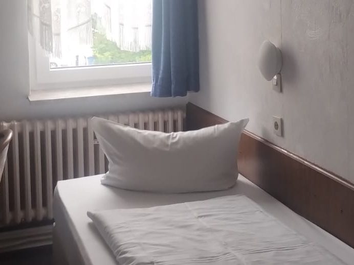 Helles Hotelzimmer mit einem Doppelbett und einer angrenzenden Sitzecke.