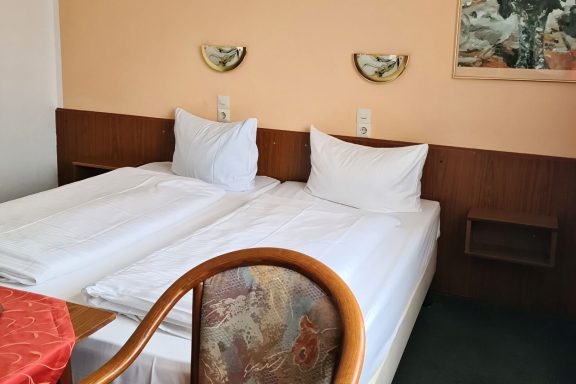 Ein schlichtes Schlafzimmer mit zwei Einzelbetten und einem Stuhl.