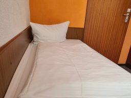 Helles Zimmer mit zwei Einzelbetten, Holzmobiliar und einem großen Fenster.