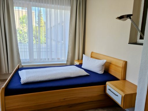 Ein Schlafzimmer mit einem Einzelbett, weißem Kissen und Nachttisch.