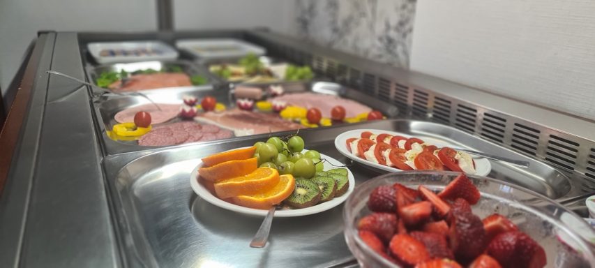 Buffet mit verschiedenen Fleisch- und Obstplatten, einschließlich Trauben und Erdbeeren.